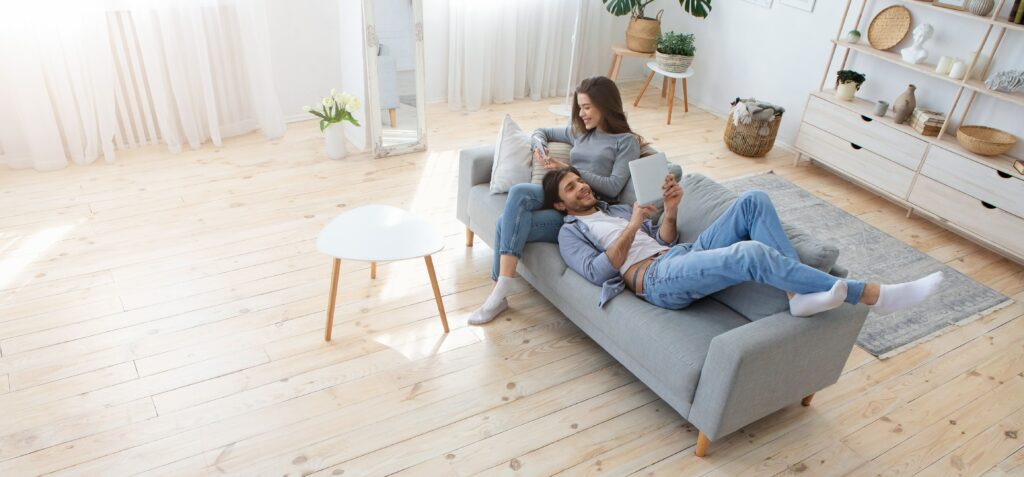 couple sitting on couch in room with wood floors