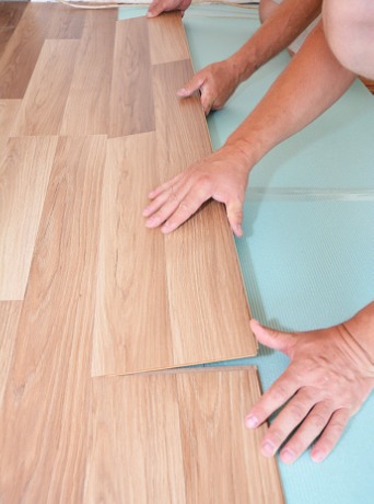 Two people installing laminate floors