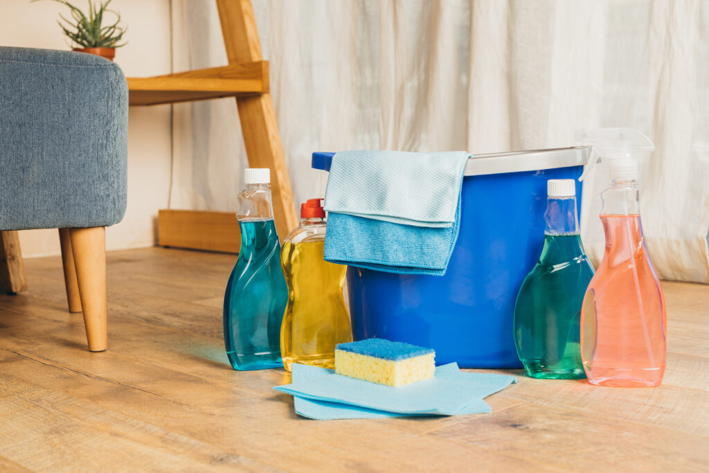 close-up view of various cleaning supplies and bucket on floor